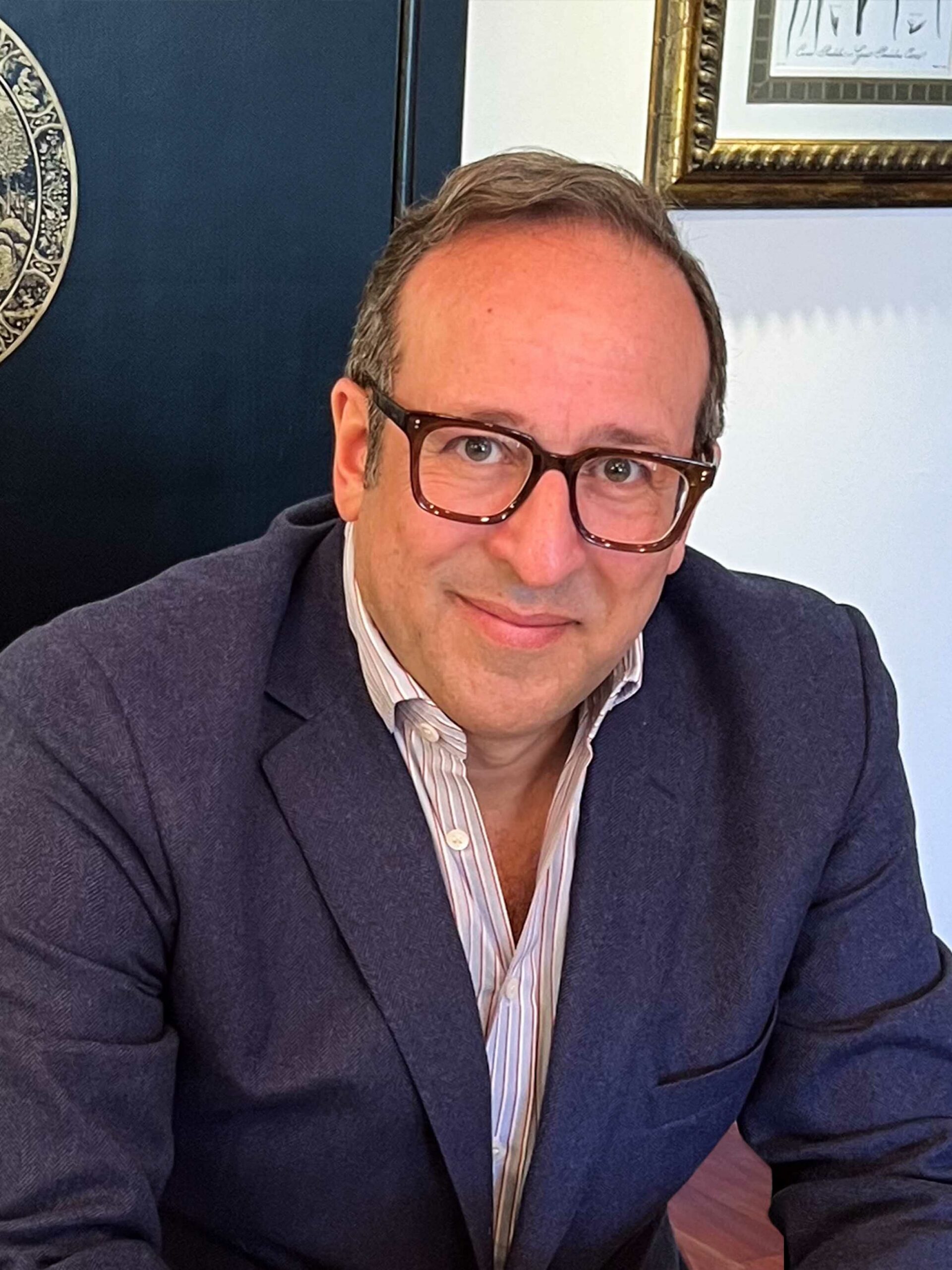 A professional headshot of a man, Alan Pinto, wearing a blue suit and dark rimmed glasses. He looks directly at the camera with a small smile.