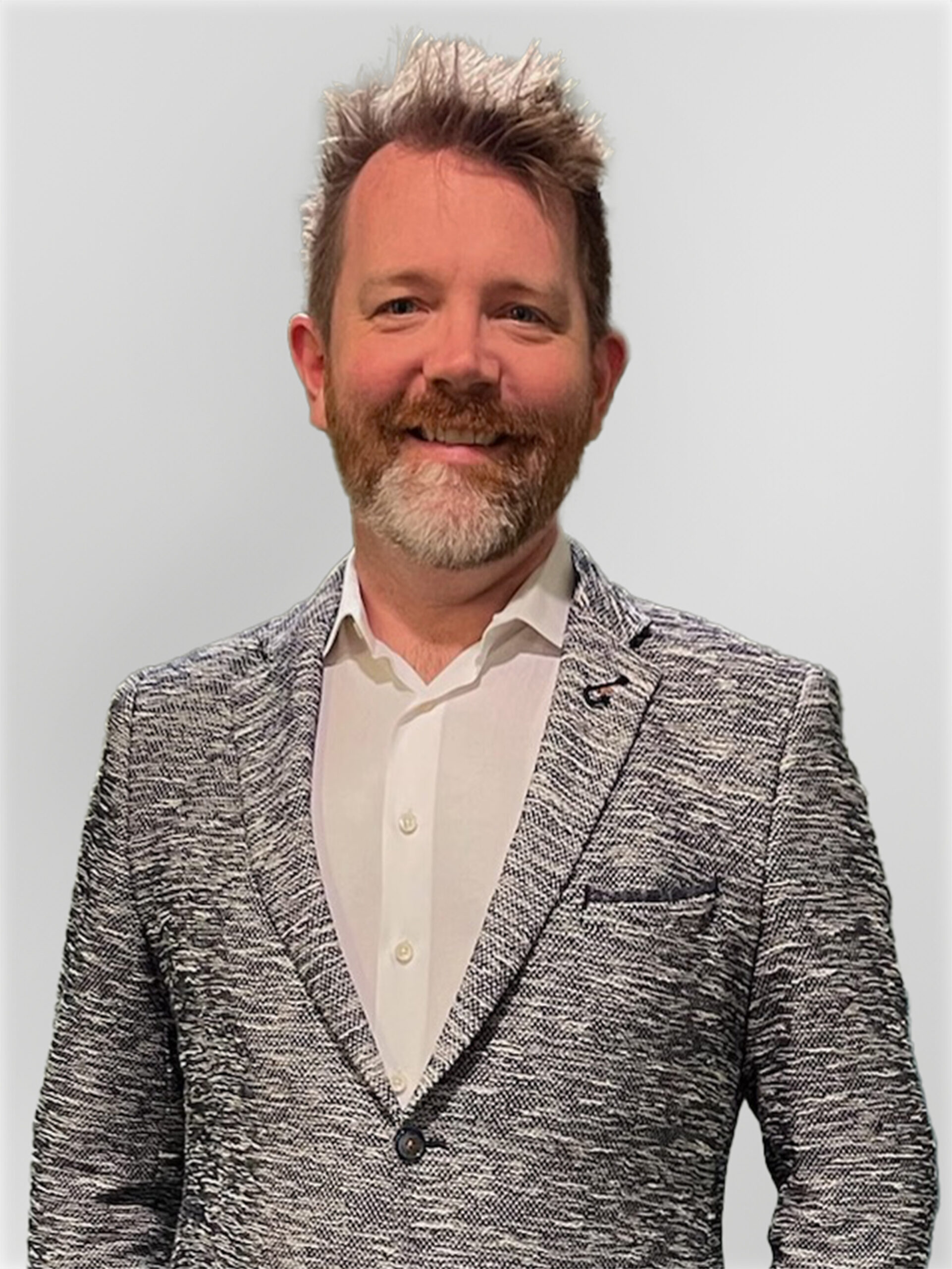 A professional headshot of a man, Michael Conn. He is wearing a white button down and gray jacket and he has short gray hair and a beard. He is smiling and looking straight ahead.