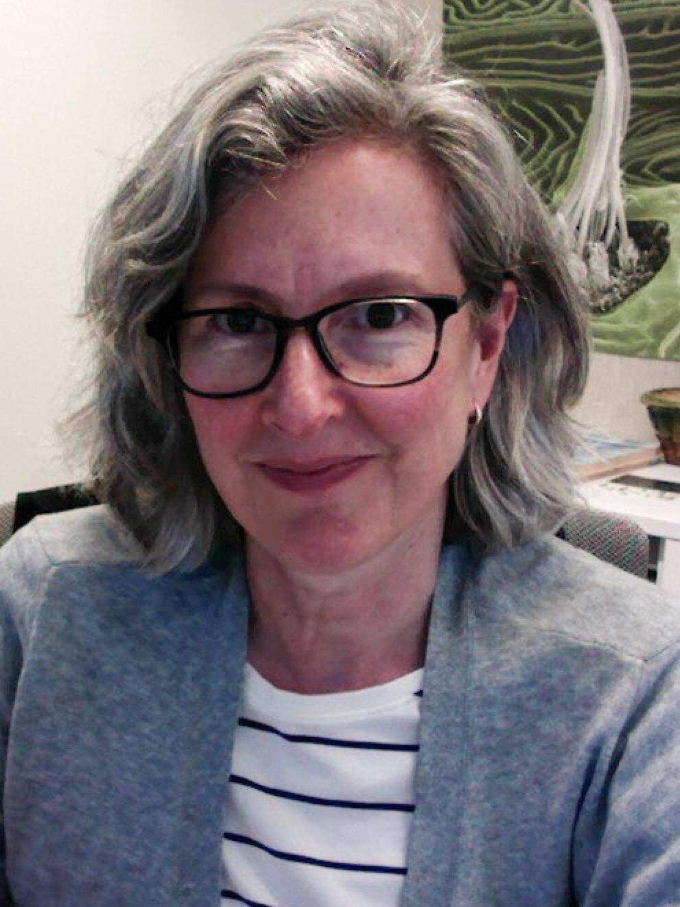 A headshot of a woman, Teresa Nicolson. She has short gray hear and is wearing glasses. She has a soft smile and looks straight ahead.