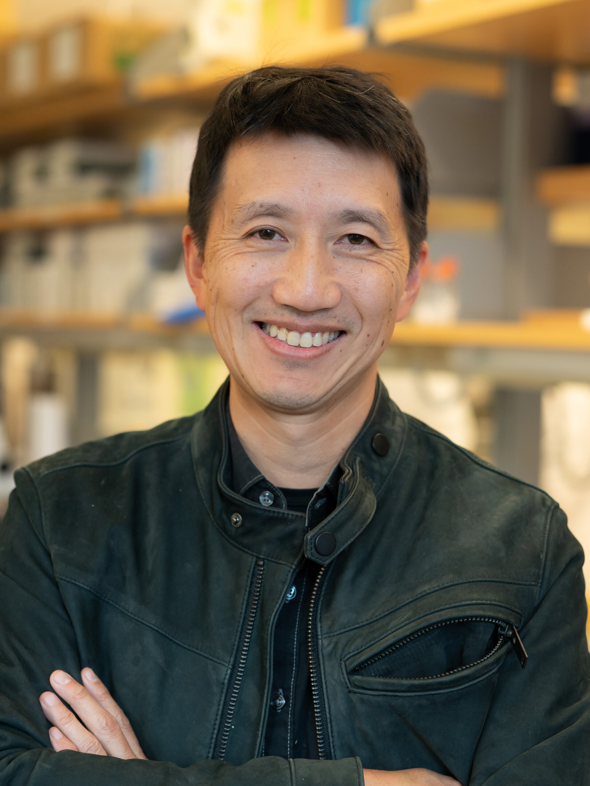 Headshot of Tim Yu. He is wearing a black shirt and jacket and has short black hair. He stands with his arms crossed and has a wide smile.