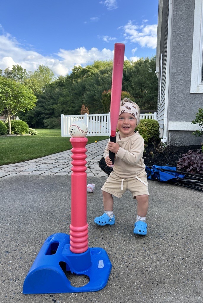 Joey Baseball Bat Joey stands outside holding a pink baseball bat and smiling big. He wear bright blue shoes