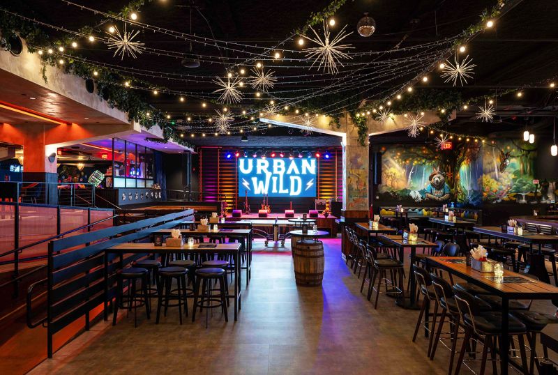 Urban Wild The interior of the Urban Wild venue in Charlestown featuring a state, string lights, and lots of tables