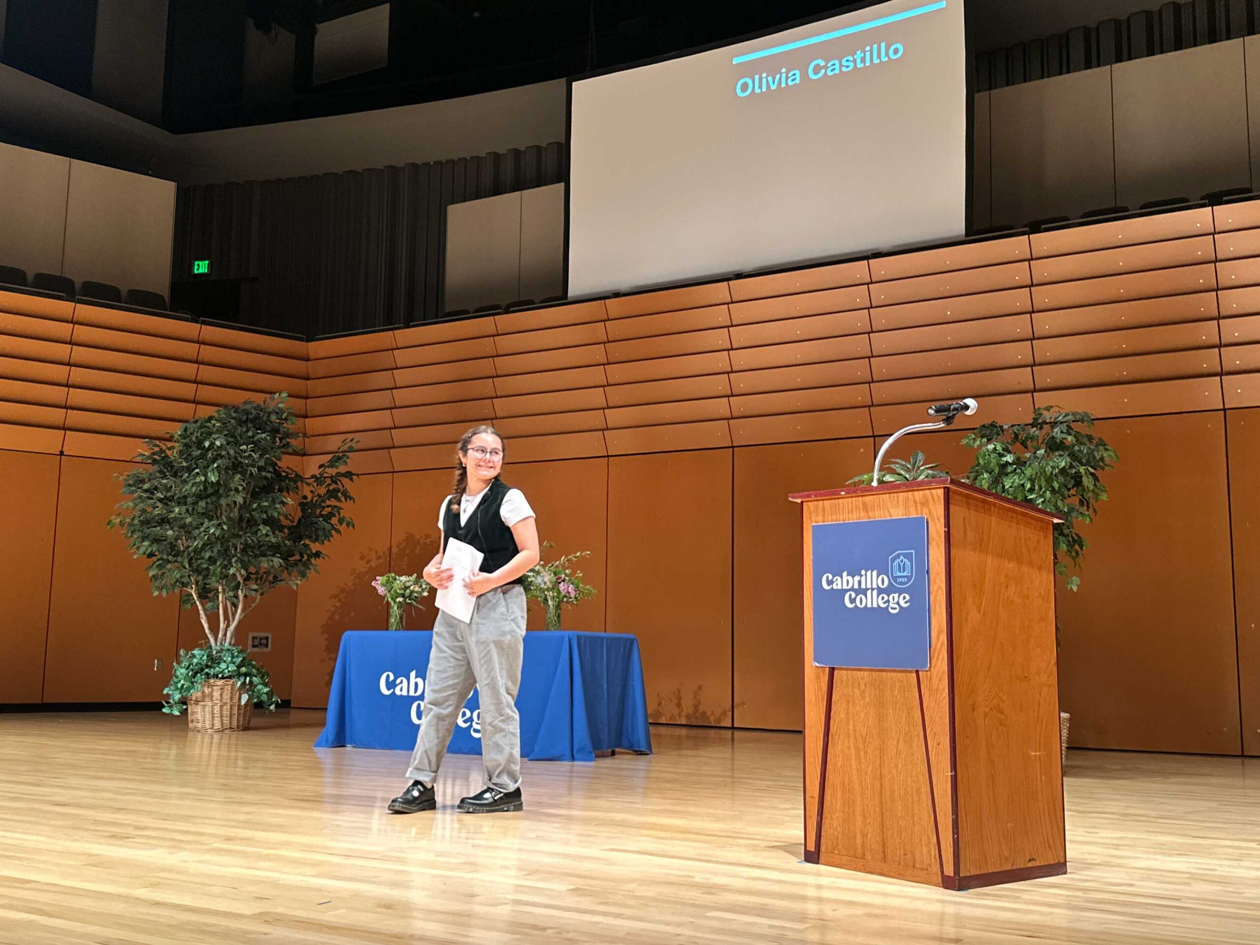  Olivia, standing on a stage, giving her speech about living with Usher syndrome