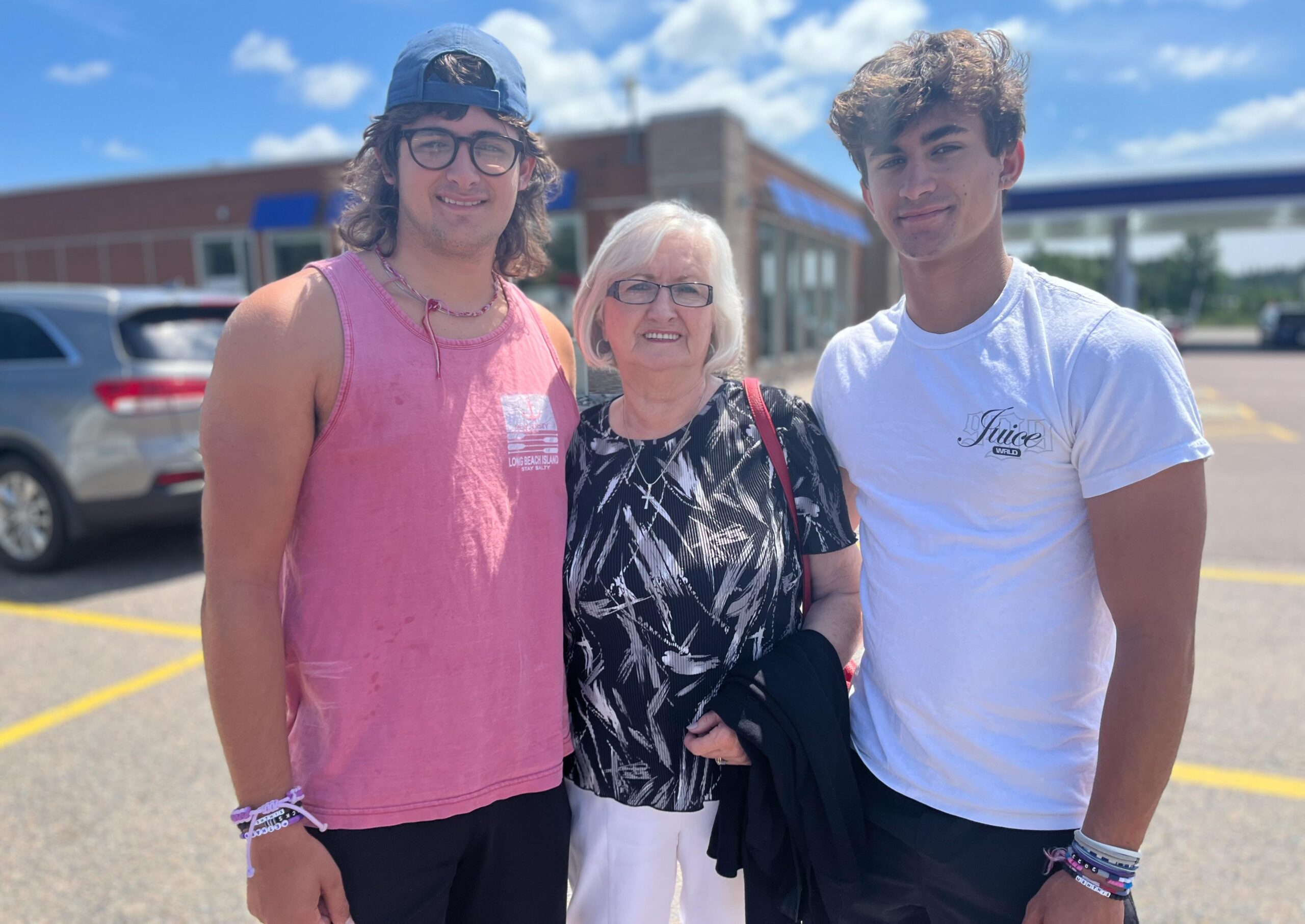 Fran stands between her two grandsons, Ethan and Gavin outside in a parking lot.