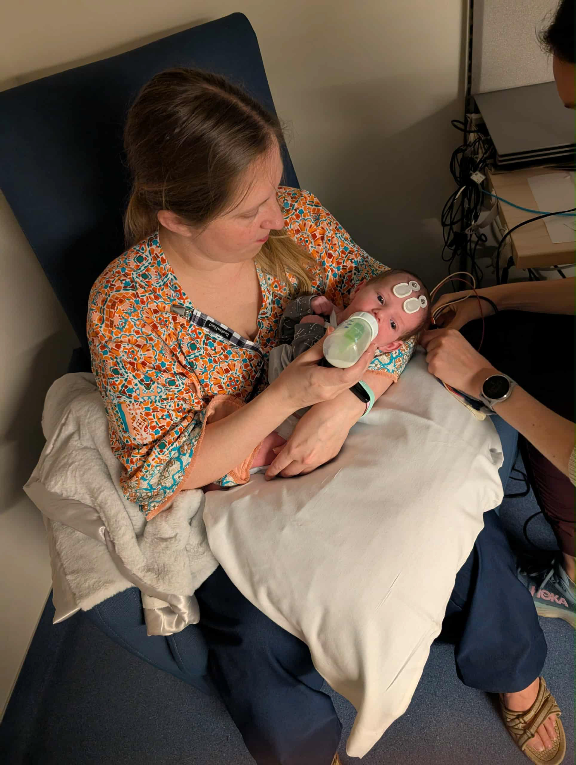 Joey is outside wearing a big hat and swinging on a swingset