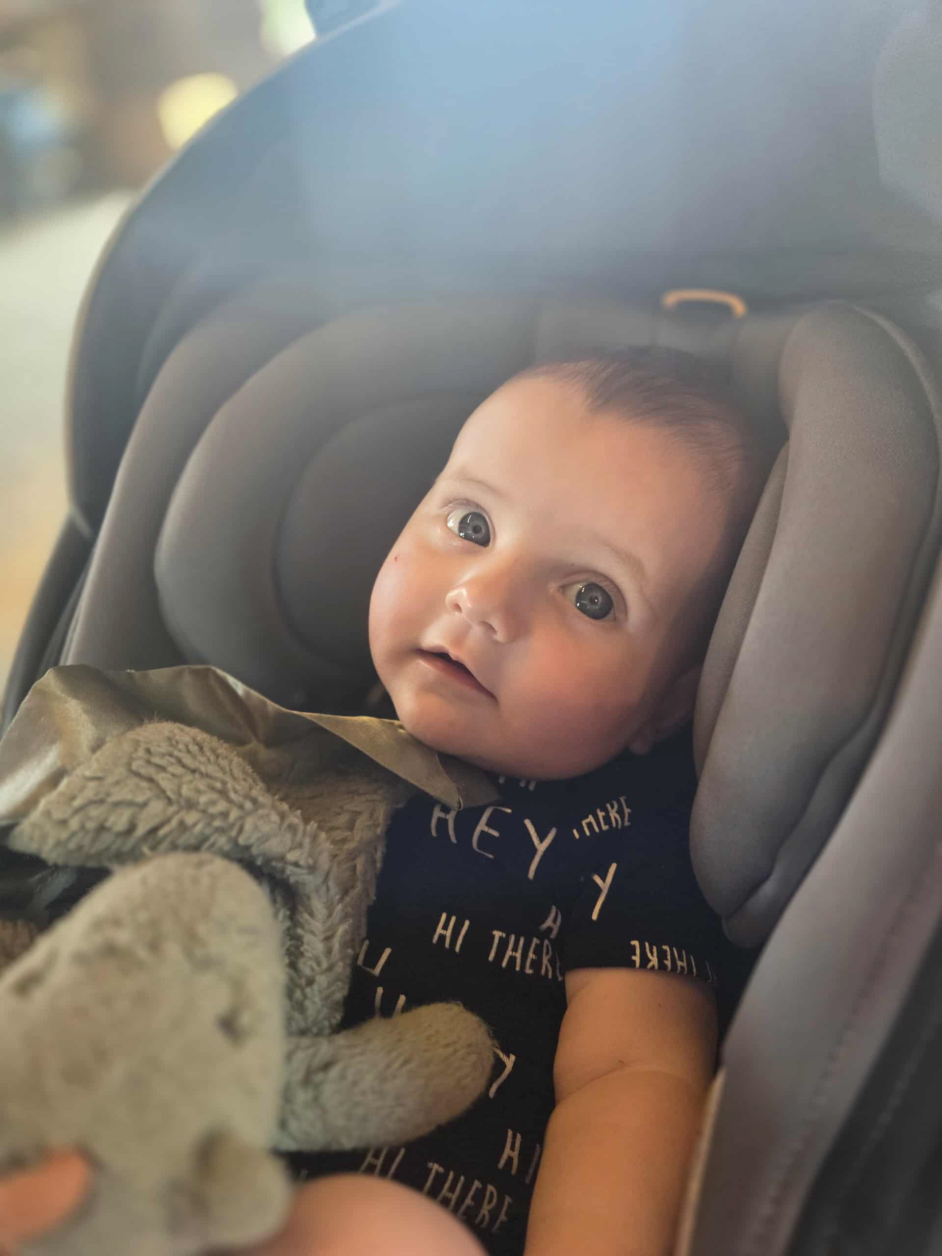 Baby Norik sits in a carseat looking directly at the camera.