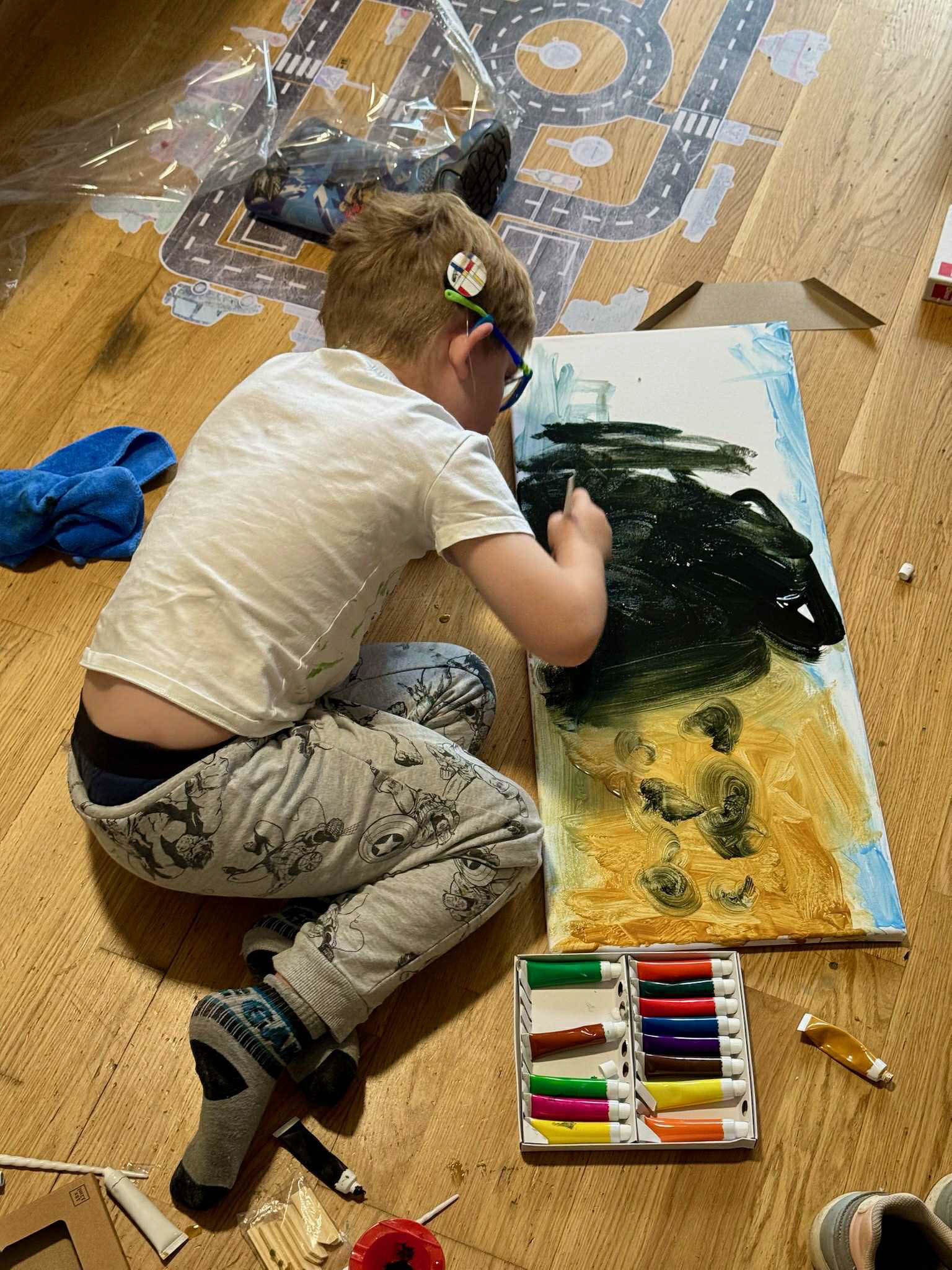 Stepanek sitting on the floor painting. You can see he has a cochlear implant on one side.