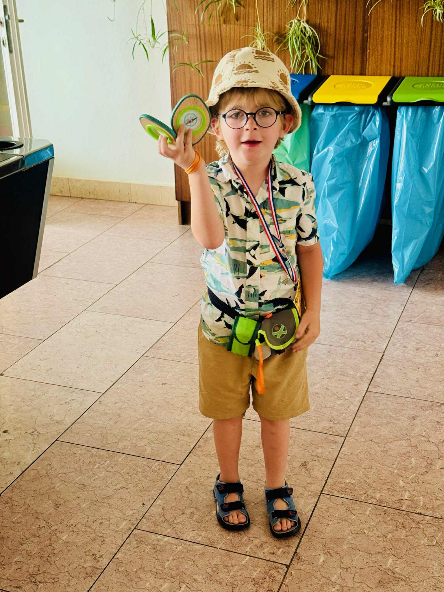 Stepanek holding a compass and smiling while wearing a patterned button down shirt and a hat