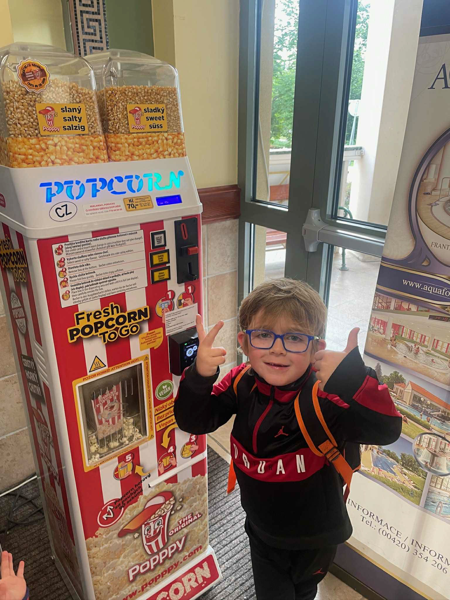 Stepanek stands next to a popcorn machine. He has blonde hair, wears glasses, and is smiling. 
