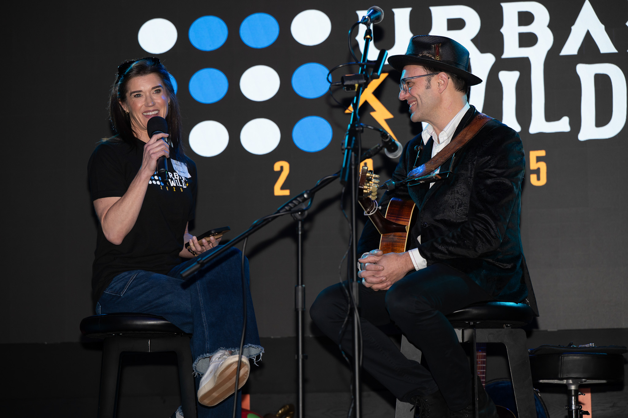 The interior of the Urban Wild venue that shows string lights, a stage, and lots of tables