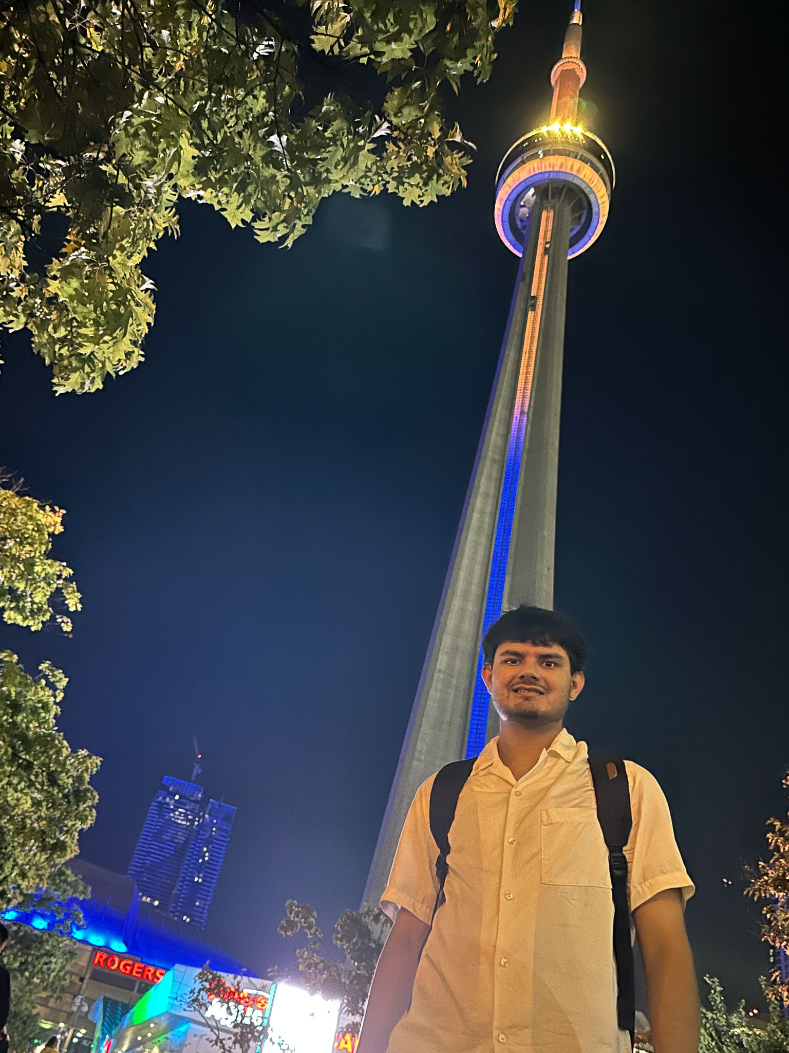 Awais standing in front of the CN Tower with blue and gold lights honoring Usher Syndrome Awareness Day 2025,