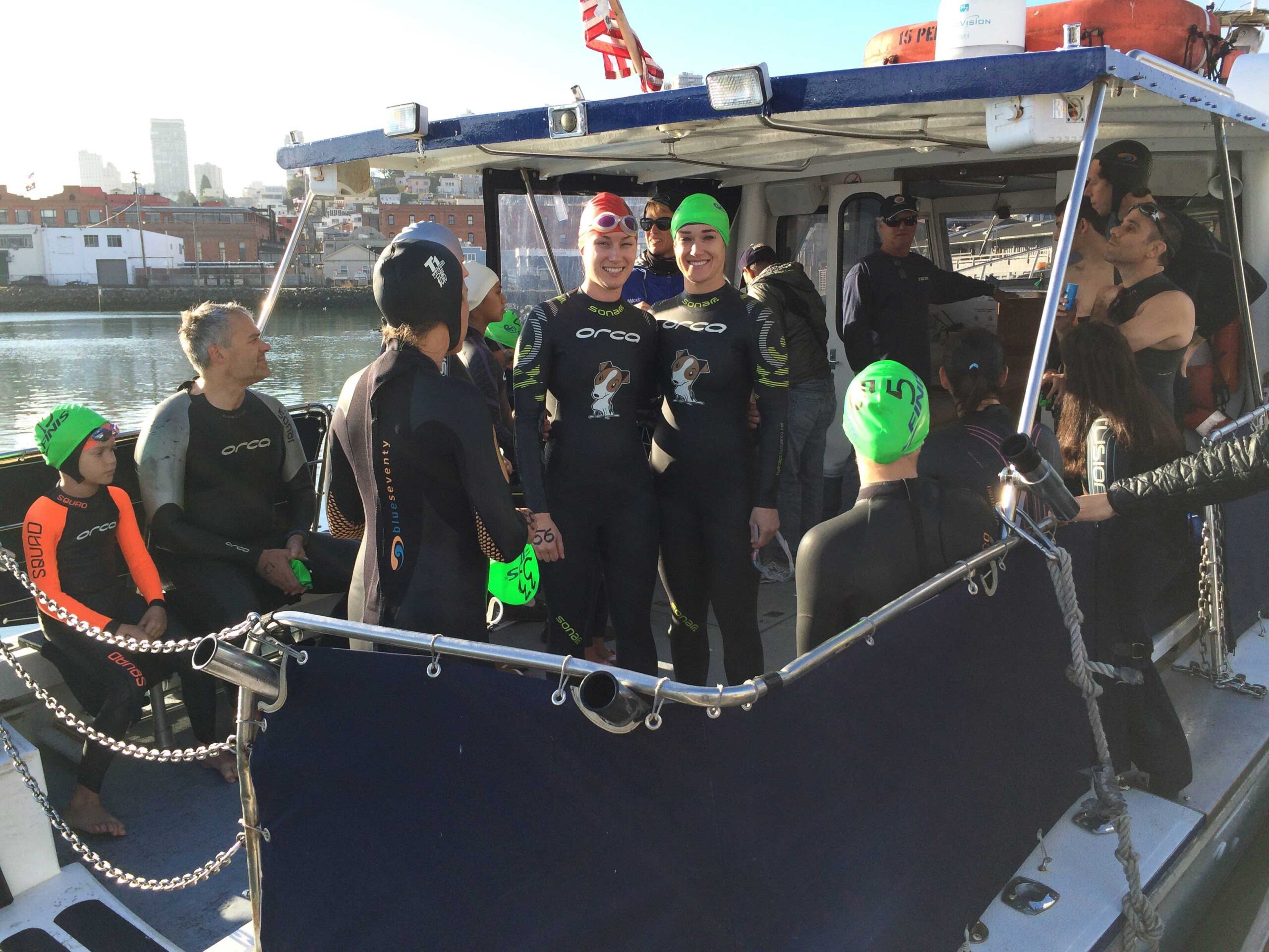 Rebecca and her friend Caroline are standing next to each other on a boat wearing wetsuits 