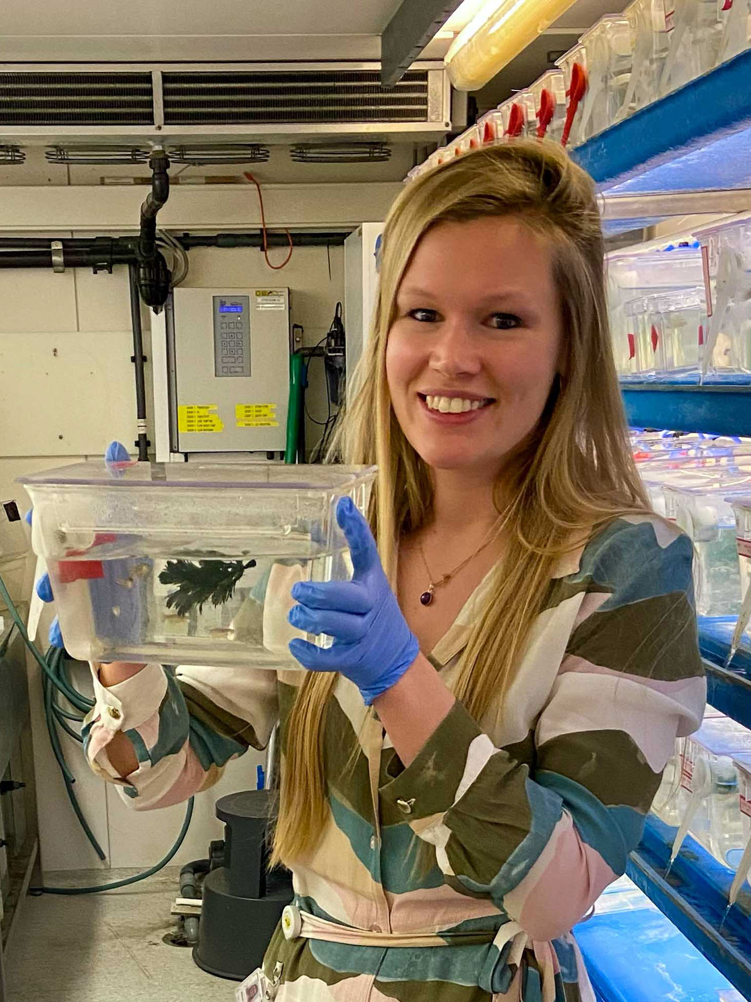 Photo of Merel Stemerdink in the lab holding up a zebrafish model.