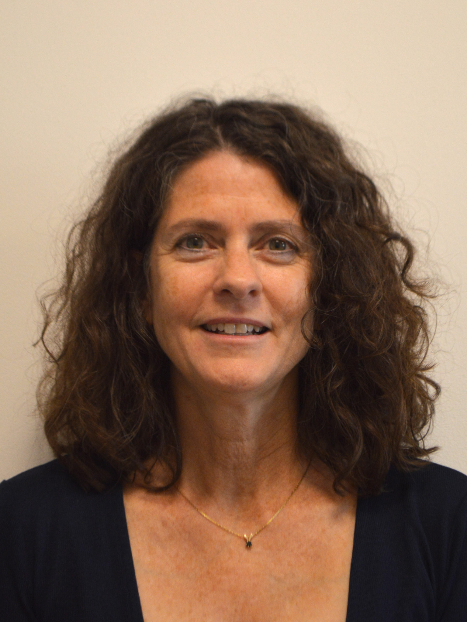Headshot of researcher Vasiliki Kalatzis. She has dark brown curly hair and looks straight ahead with a smile.