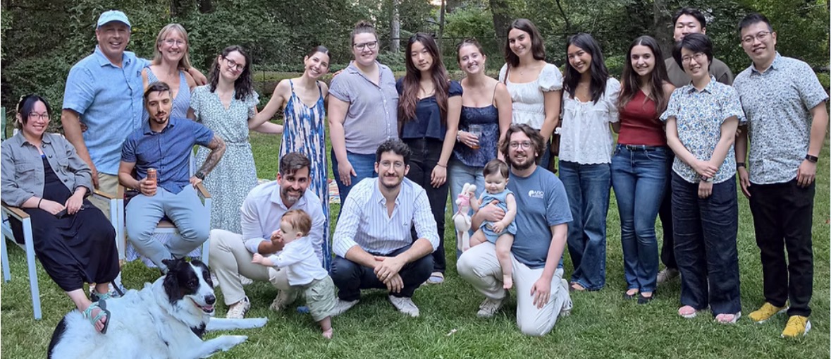 A group of about 20 people pose together outdoors in a park
